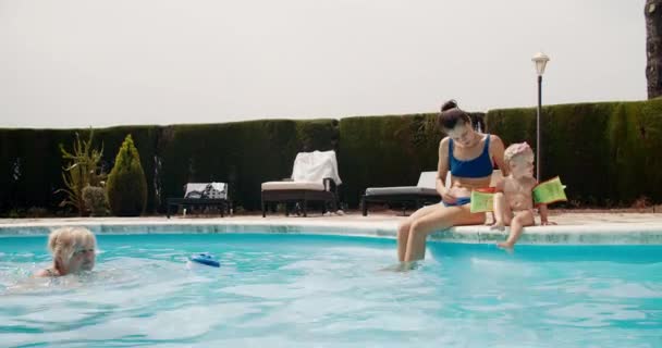 Máma s dcerou sedí před bazénem babička plavání — Stock video