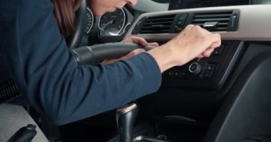 Aracın içini elektrikli süpürgeyle temizleyen genç bir kadın.