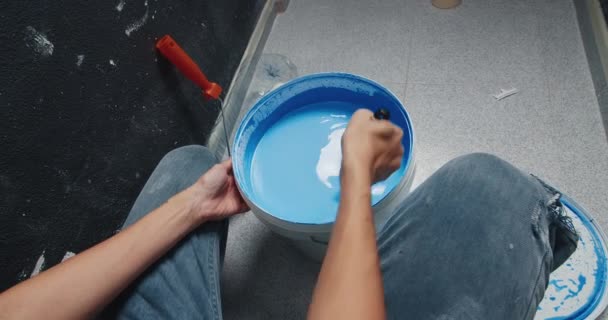 POV mujer joven mezclando pintura azul en cubo preparándose para las reparaciones en el hogar — Vídeo de stock