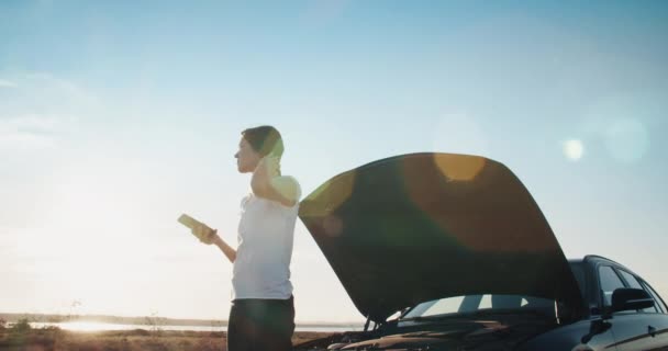 Mujer joven en frente de coche de avería utilizando el servicio de llamadas de teléfonos inteligentes en la carretera — Vídeos de Stock