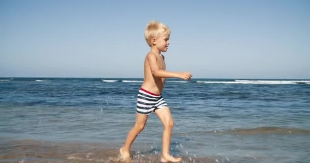 Szczęśliwe dziecko biegające i uśmiechnięte na plaży nad morzem na wakacjach letnich — Wideo stockowe