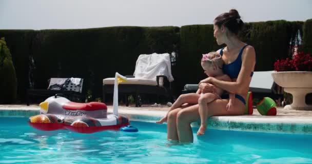 Mama z córką siedzi przed basenem dziecko skacze do wody — Wideo stockowe
