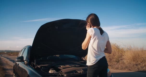 Jovem na frente do carro avaria usando o serviço de chamada de smartphone na estrada — Vídeo de Stock