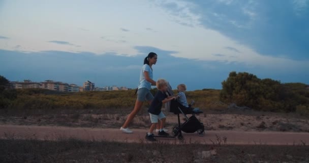 Familia caminando juntos al aire libre en la noche mamá y los niños en la puesta del sol — Vídeo de stock