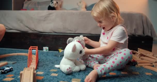 Χαριτωμένο χαρούμενο κοριτσάκι παίζει με λούτρινα παιχνίδια ζώων το βράδυ στο σαλόνι — Αρχείο Βίντεο