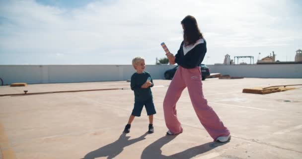 Young mother with son having fun exploding firecracker confetti — Stock Video