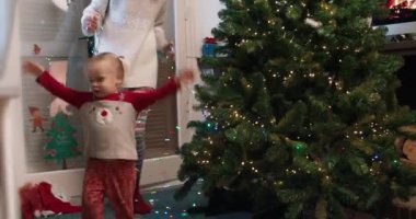 Mutlu neşeli aile Noel ağacını süslüyor, anne ve çocuklar birlikte dans ediyor.