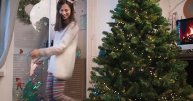 Çekici bir kadın çelenk ve Noel ağacı süsleme ile dans ediyor.