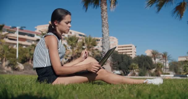 Внештатная деловая женщина сидит и думает о зеленой траве, работающей с ноутбуком — стоковое видео
