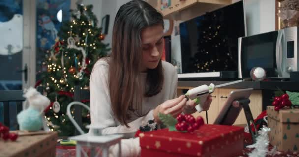 Ελκυστική γυναίκα κάνοντας χειροποίητα χριστουγεννιάτικο δώρο στο σπίτι χρησιμοποιώντας το πιστόλι κόλλας — Αρχείο Βίντεο