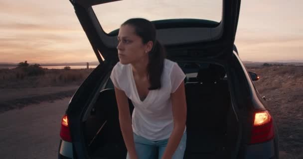 女は座ってスマホを使うよりトランクの中で何かを探す — ストック動画