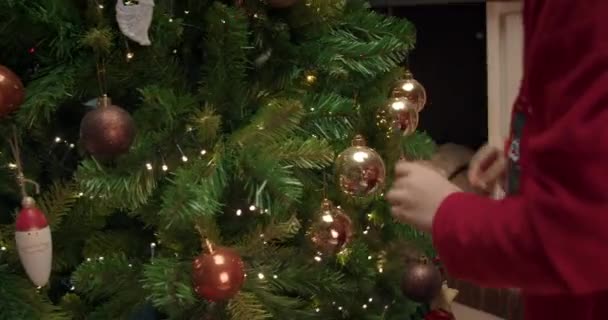 Dzieci ręce zbliżenie dekorowanie choinki z piłką — Wideo stockowe