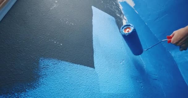 Close-up vrouw handen bekijken van onder het schilderen van zwarte muur naar blauw met behulp van roller — Stockvideo