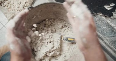 İlk bakışta adam ellerini çimento harçına çakıl ekleyip karıştırıyor.