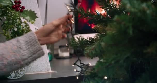 ผู้หญิงมือใกล้ชิดตกแต่งต้นคริสต์มาสกับการ์แลนด์แสงในบ้าน — วีดีโอสต็อก