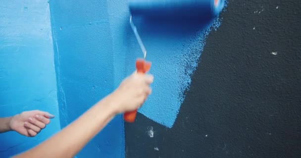 Mujer mano primer plano pintura negro pared sobre azul con rodillo de pintura en el apartamento — Vídeos de Stock