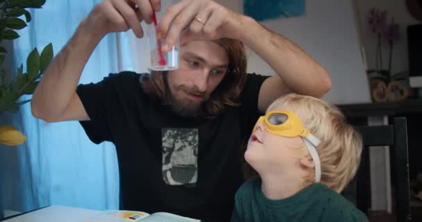 Ayah muda dengan anak laki-laki membuat kimia kristal percobaan di rumah — Stok Video