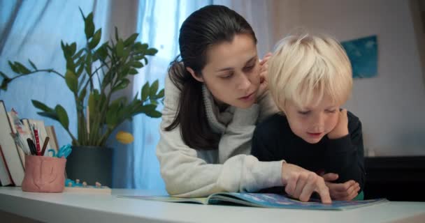 Ibu muda dengan anak prasekolah membaca buku dengan labirin — Stok Video