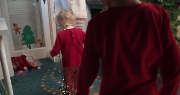 Gyerekek játszanak karácsonyfa dekoráció koszorú — Stock videók