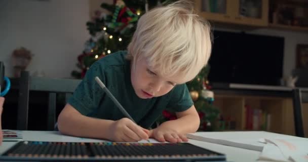 Cute child boy drawing with pencil sitting at the table on Christmas holidays — Video Stock