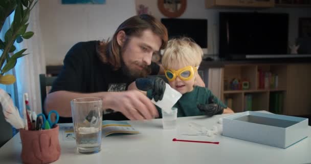 Família pai e filho fazendo experiências químicas em casa juntos — Vídeo de Stock