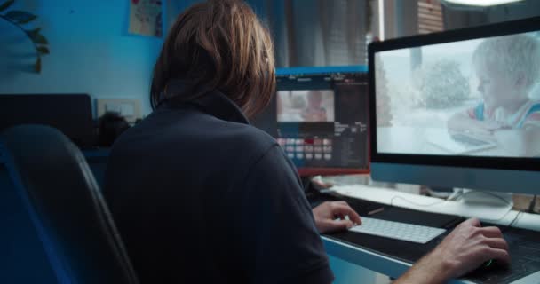 Zadní pohled na mladého muže na volné noze, který edituje video na počítači — Stock video