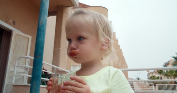 Schattig baby meisje drinken biologische tomaat sap van glas buiten — Stockvideo