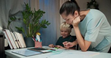 Happy homeschool family make homework and mum help to son with art lesson