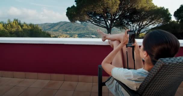 Grande colpo giovane donna sul balcone al tramonto utilizzando smartphone chat e sorridente — Video Stock
