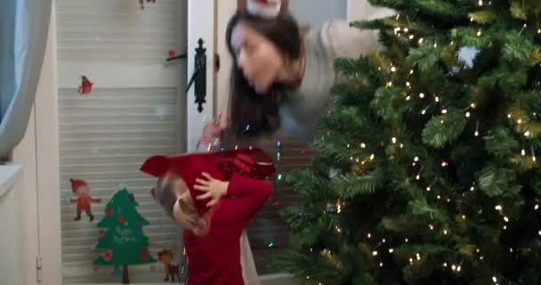 แม่สาวที่มีเด็กตกแต่งต้นคริสต์มาสบนห้องนั่งเล่นในตอนเย็น — วีดีโอสต็อก