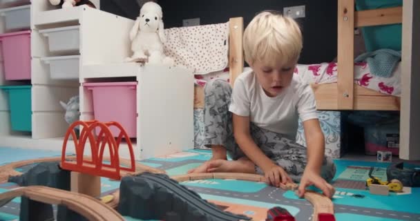 Cute szczęśliwy chłopiec gry drewniane drogi zabawka w pokoju dzieci — Wideo stockowe