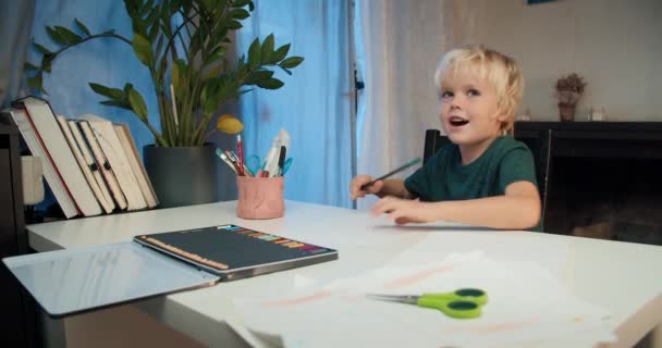 Mignon dessin de garçon enfant avec crayon assis à la table sur le salon — Video