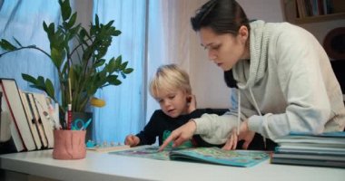 Anne ve oğul oturma odasında kitap okuyorlar.