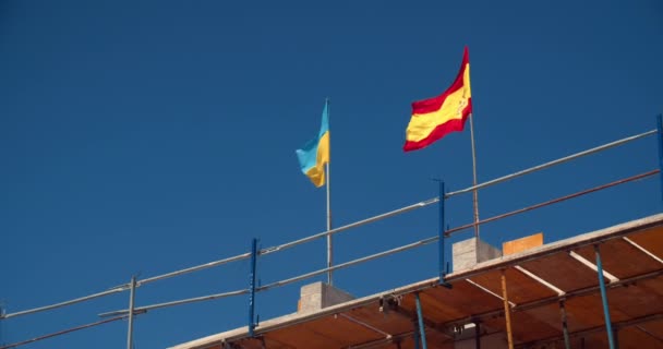 Španělská a ukrajinská vlajka nad budovou ve výstavbě — Stock video