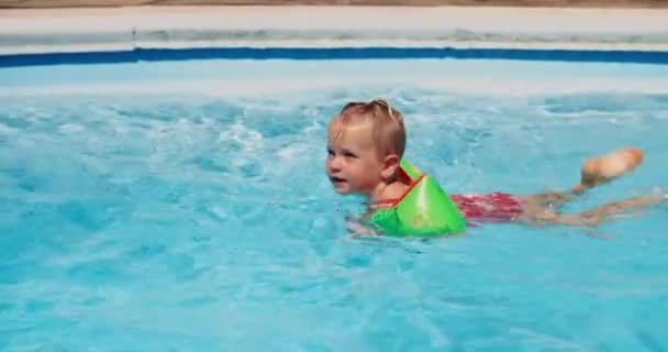 Cute child girl learning to swim in swimming pool on summer vacations — 图库视频影像