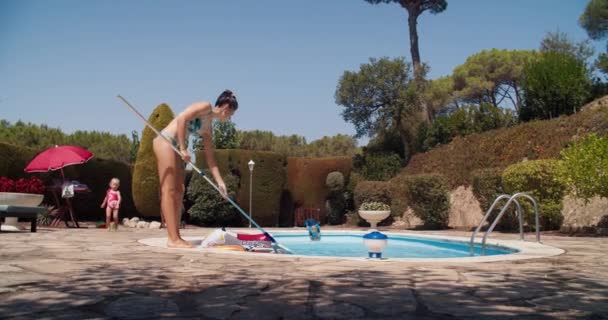 Νεαρή γυναίκα καθαρίζει την πισίνα χρησιμοποιώντας skimmer χέρι την καλοκαιρινή μέρα — Αρχείο Βίντεο
