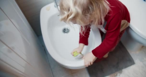 Мила дівчинка прибирає біде у ванній кімнаті, допомагаючи мамі — стокове відео