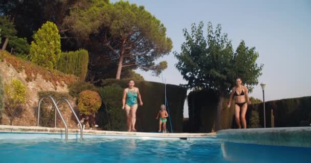 Веселая семья бежать и прыгать в бассейн — стоковое видео