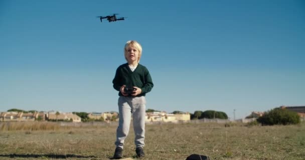 Niño jugando con mini juguete drone al aire libre utilizando el mando a distancia — Vídeo de stock