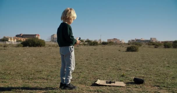 Παιδί αγόρι παίζει με μίνι κηφήνας παιχνίδι σε εξωτερικούς χώρους χρησιμοποιώντας τηλεχειριστήριο — Αρχείο Βίντεο