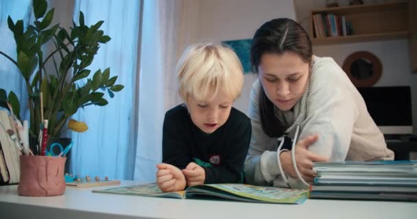 Young mother with preschool child boy reading the book with labyrinths — Video Stock