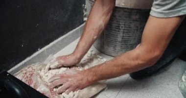 Men hands closeup adding gravel to cement during house repair