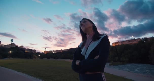 Young woman enjoying of walking in public park on evening sunset — стоковое видео