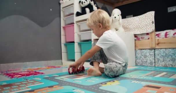 Lindo niño jugando con camión de bomberos de juguete en el dormitorio del niño en casa — Vídeos de Stock