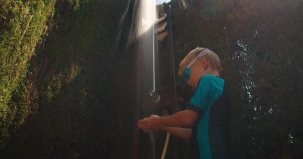 Niño feliz jugando con agua en la ducha de la piscina al aire libre — Vídeo de stock