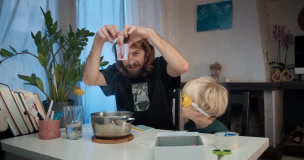 Tânărul tată cu un copil care face experimente cu cristale chimice acasă — Videoclip de stoc