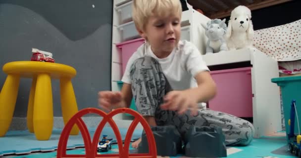 かわいい幸せな男の子は子供部屋で木製の鉄道のおもちゃをプレイ — ストック動画