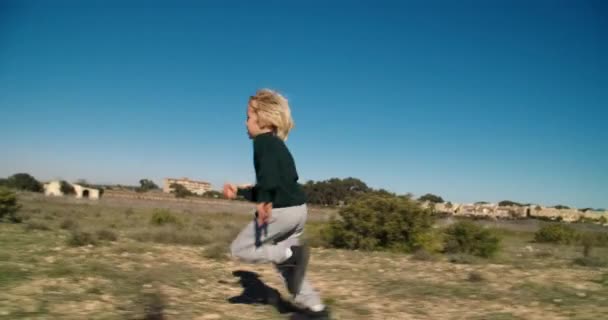 Bambino spensierato ragazzo sta correndo sul campo di campagna al giorno — Video Stock