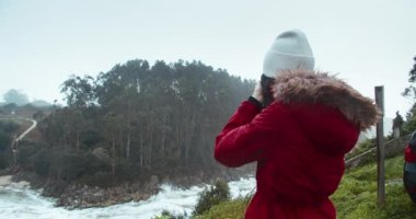Female travel photographer shoot stormy beach day of bad weather and big waves