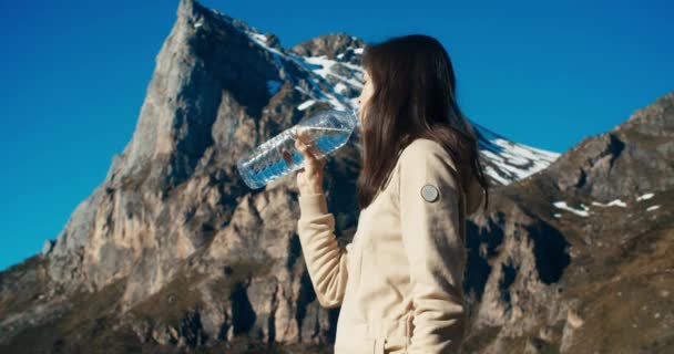 Young adult woman drink water on mountain travel — Vídeo de stock